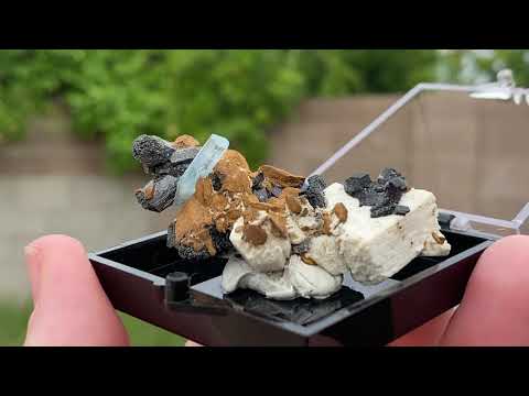 Aquamarine in feldspar with black tourmaline and siderite which is a pseudomorph. This specimen comes from The Republic of Namibia, Southern Africa.